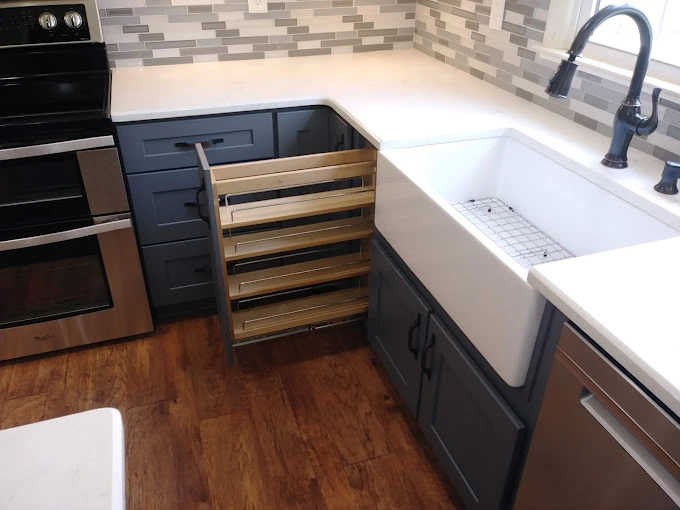 Spice rack pull out for kitchen cabinets near white kitchen sink.
