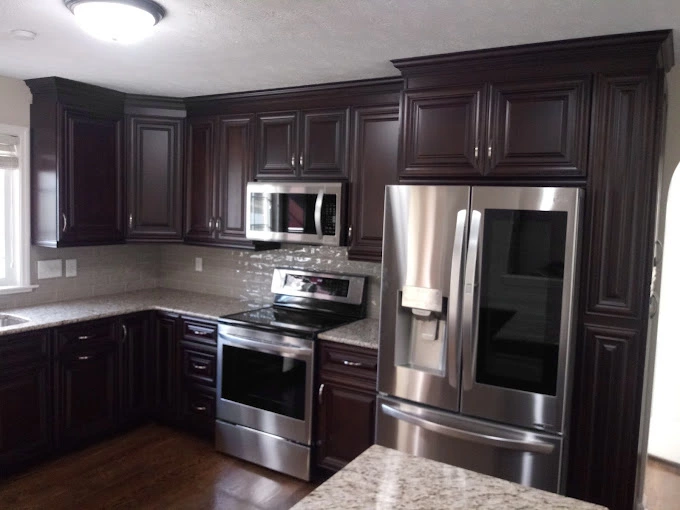 Dark brown kitchen cabinets with silver appliances and wood flooring installation near Fayetteville NC